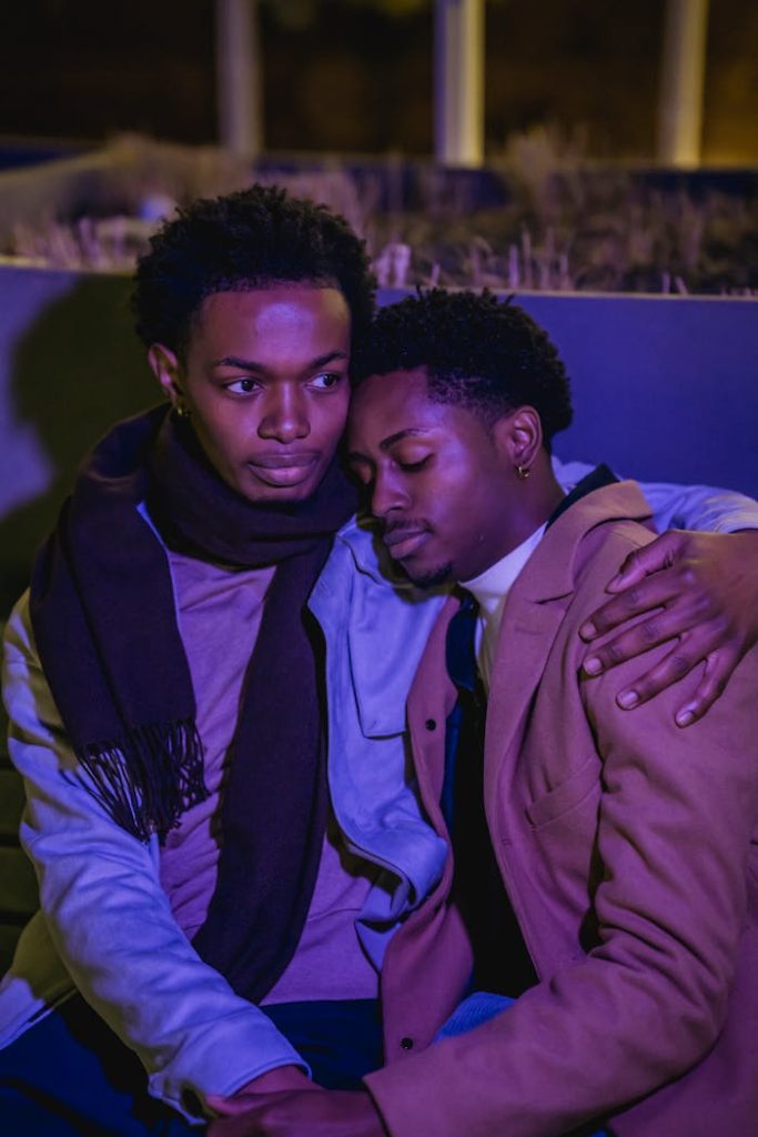 Black male couple embracing tenderly on bench